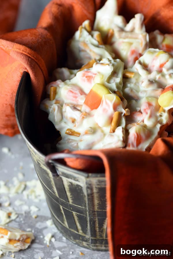 Candy Corn Pretzel Bark is the ultimate Halloween treat with white chocolate, candy corn, and pretzels! Candy Corn Pretzel Chocolate Bark in serving container