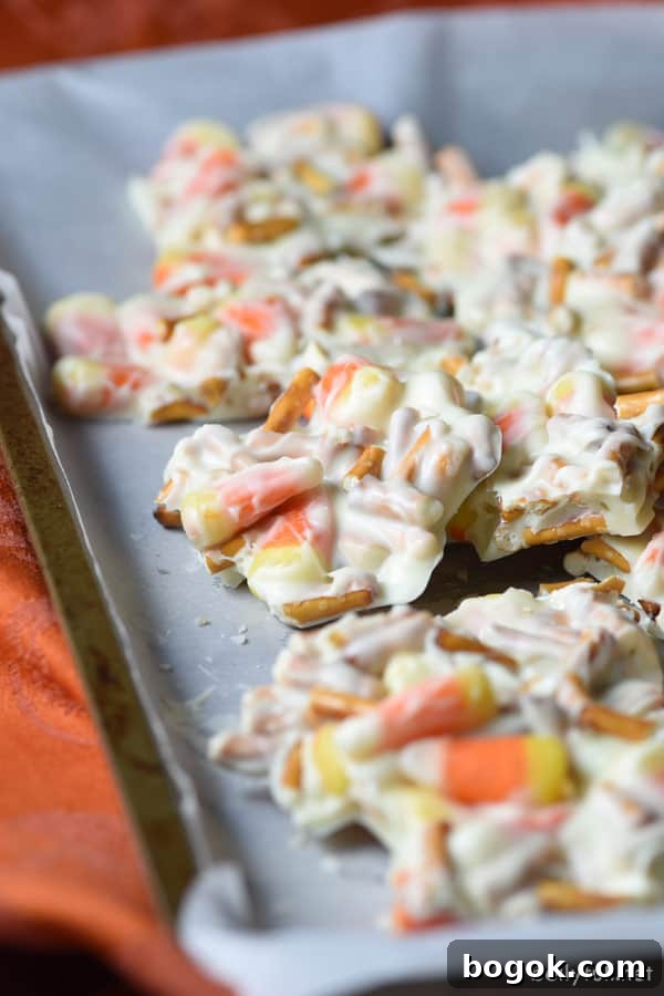 Candy Corn Pretzel Bark is the ultimate Halloween treat with white chocolate, candy corn, and pretzels! Candy Corn Pretzel Chocolate Bark on parchment paper