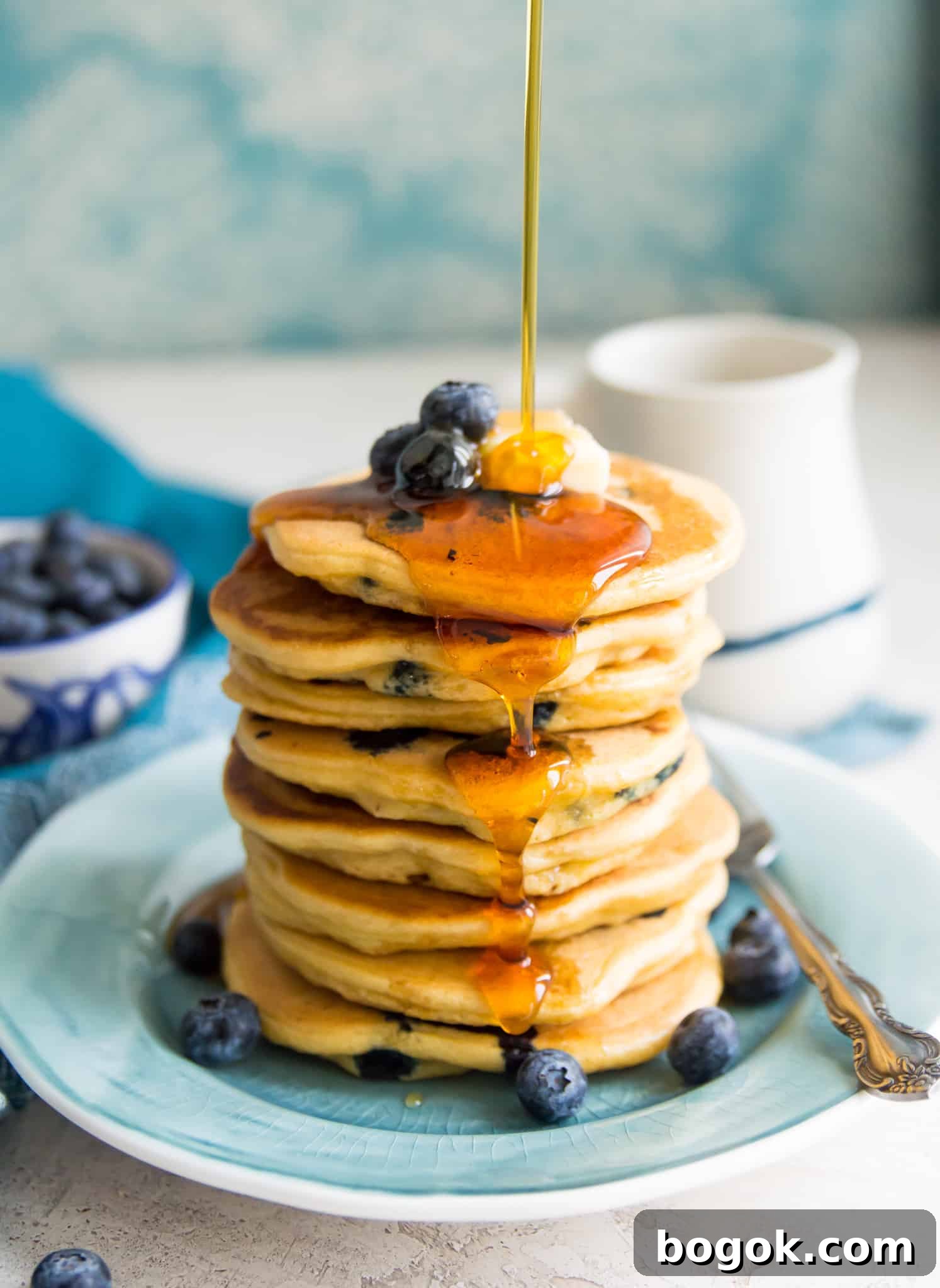 Fluffy Paleo Blueberry Pancakes: Grain-Free Breakfast Recipe 2 A stack of paleo blueberry pancakes with syrup being poured on them.