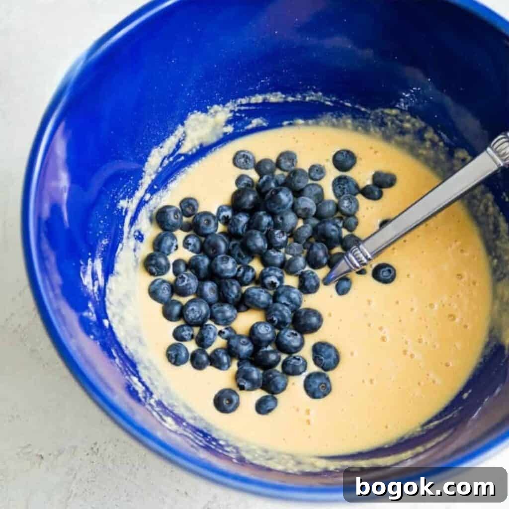 Fluffy Paleo Blueberry Pancakes: Grain-Free Breakfast Recipe 6 A bowl filled with a blueberry pancake batter with a spoon in it.