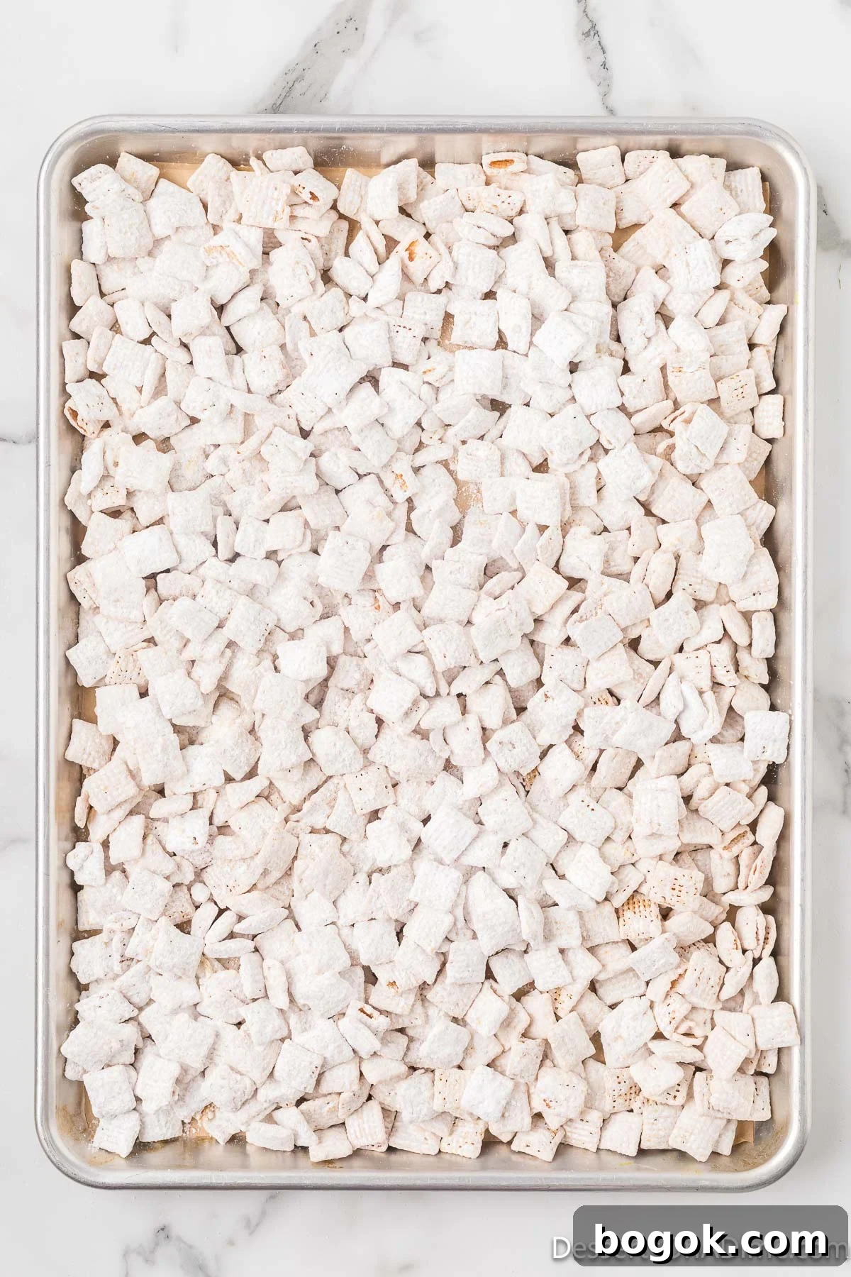 Lemony Puppy Chow Recipe: Zesty No-Bake Snack Mix 9 Cereal mixture spread on baking sheet.