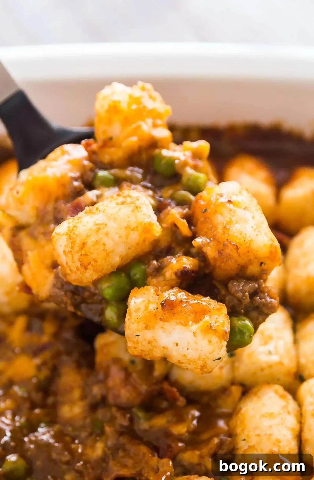 Bacon Cheeseburger Tater Tot Casserole Recipe 2 A spoon holding up a scoop of cheeseburger tater tot casserole from the pan.