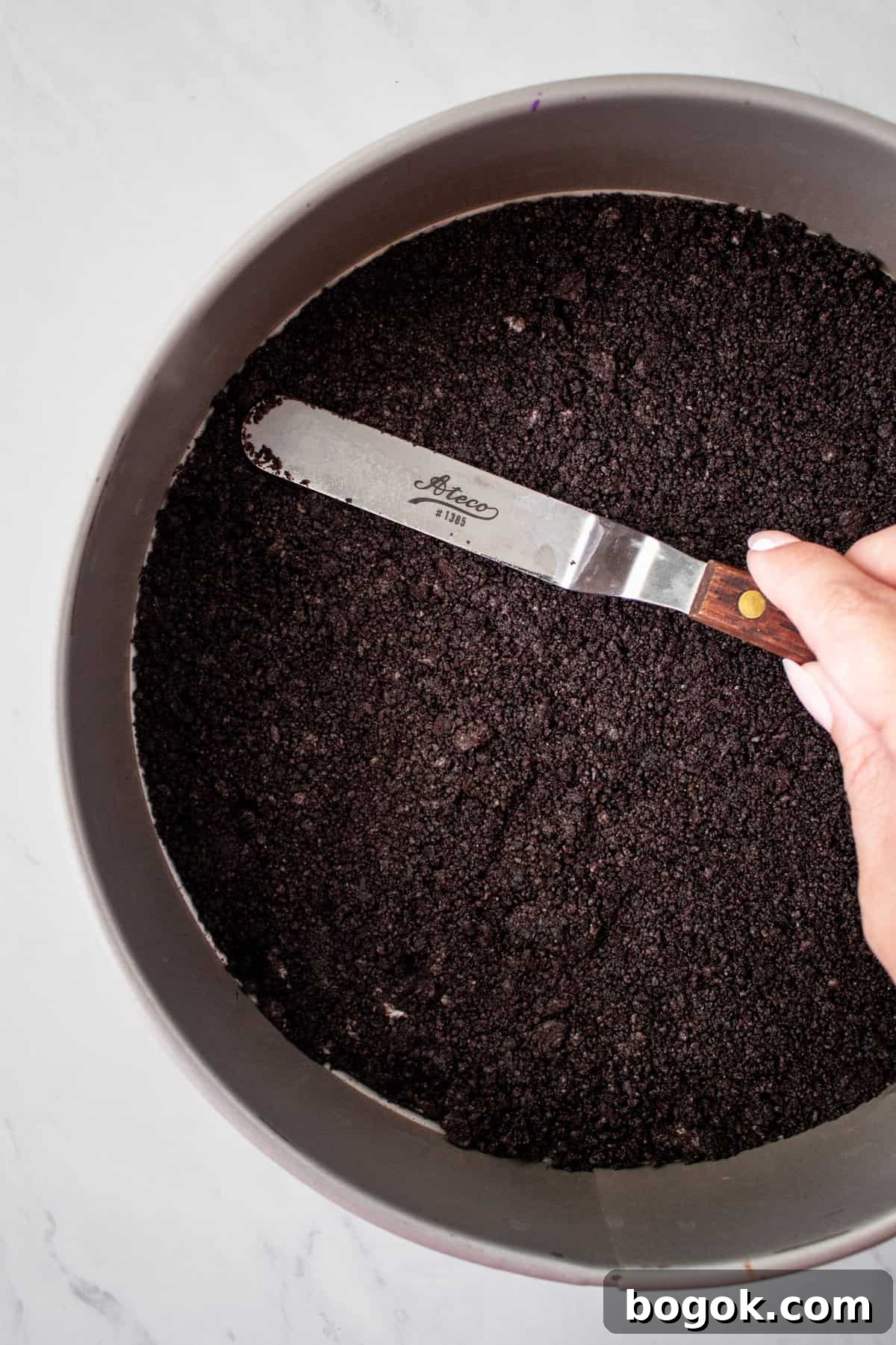 oreo crust being smoothed in the bottom of a pie tin