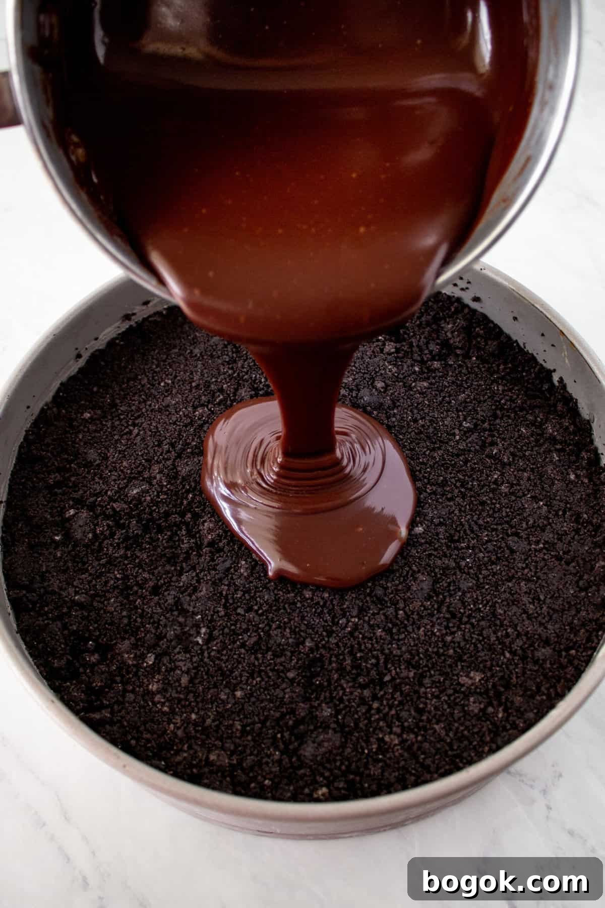 chocolate fudge being poured over a layer of chocolate crust
