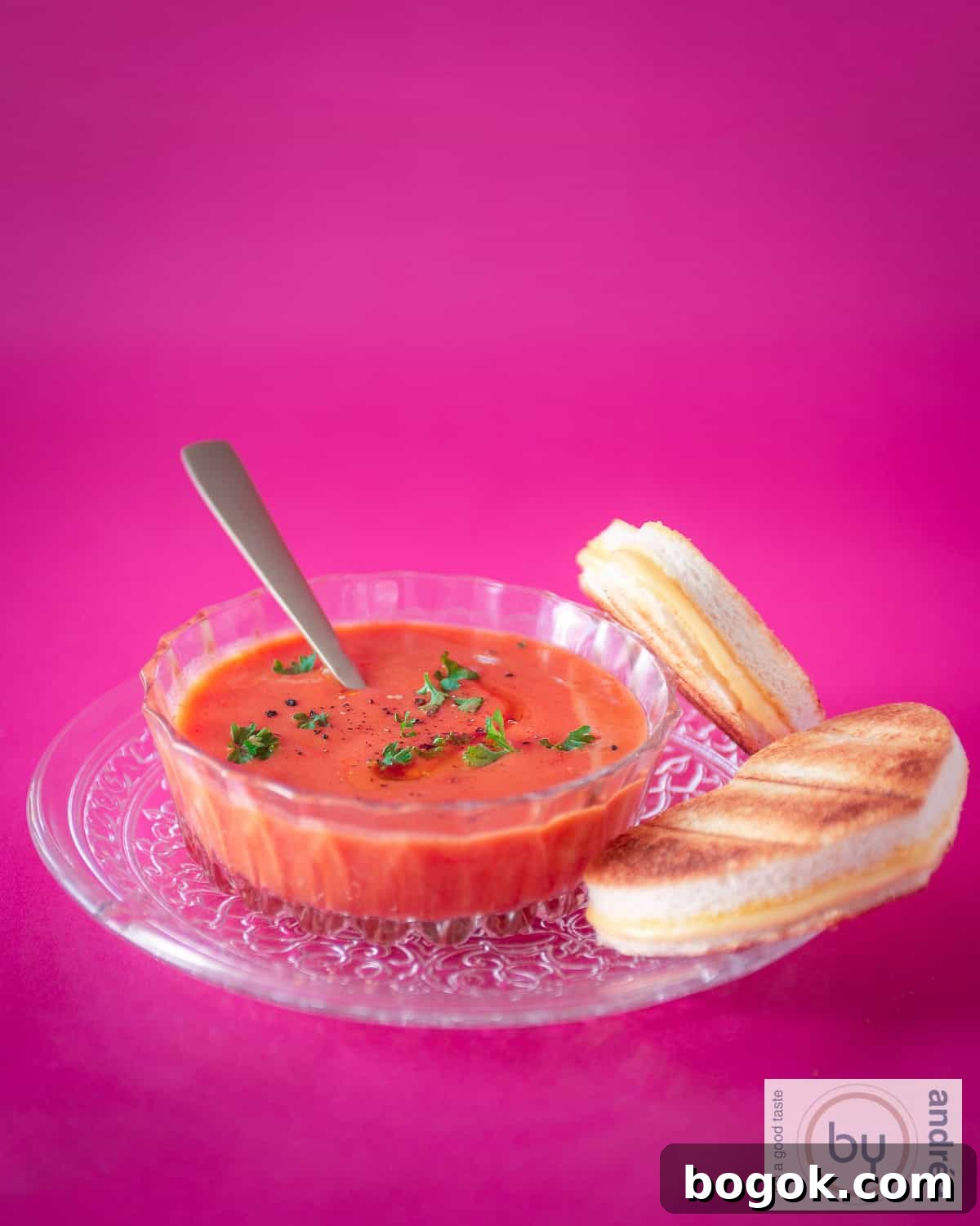 Herbed Tomato Soup with Cheesy Toastie 3 A height photo with a pink background, a glass plate with tomato soup in a glass bowl and heart-shaped toasted sandwiches