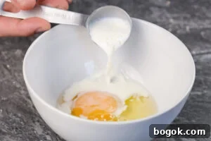milk added to bowl with egg in a white bowl