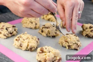 Rock cakes being placed on a silicone mat by hands and fork