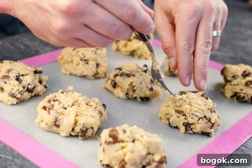 Rock cakes being placed on a silicone mat by hands and fork