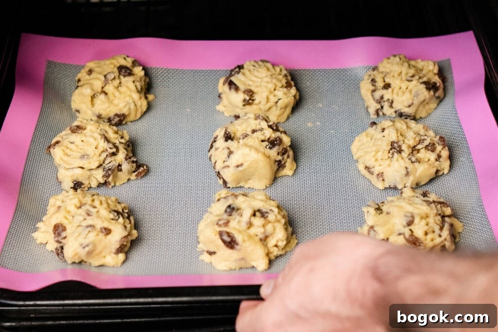 9 rock buns on a silicone mat on a baking tray being put into an oven