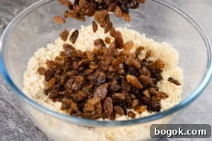 sultanas added into flour and butter cake mix in a glass bowl