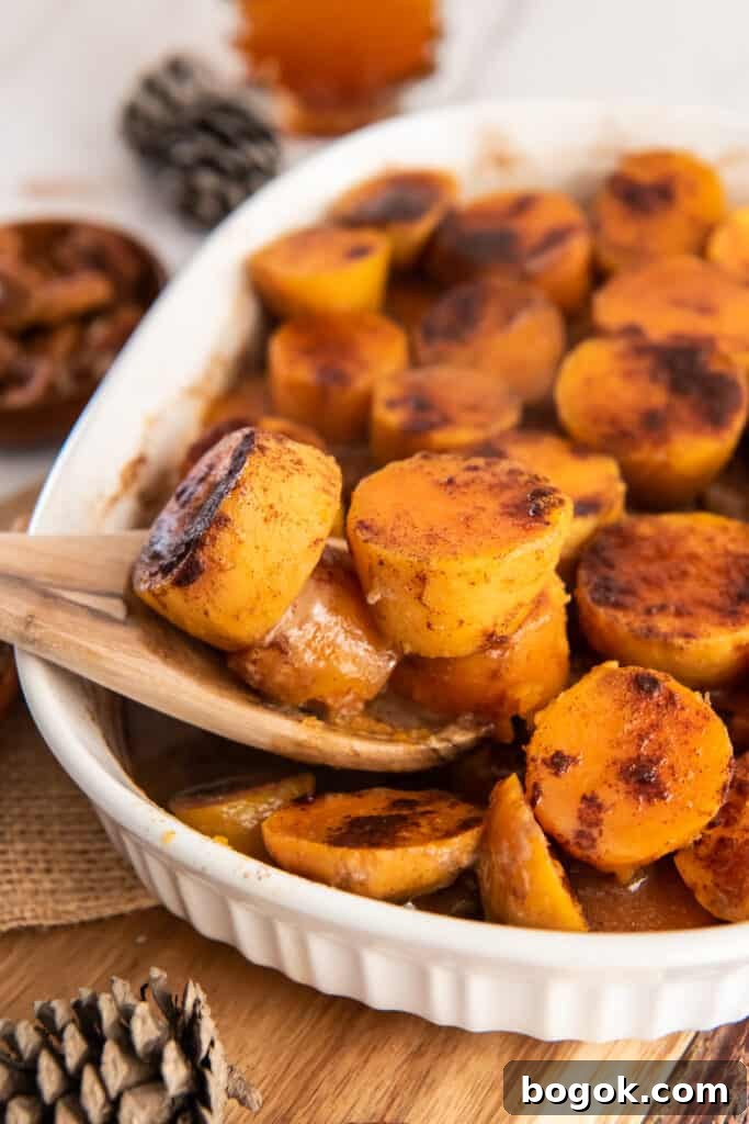 Maple glazed sweet potatoes being scooped with a wooden spoon.