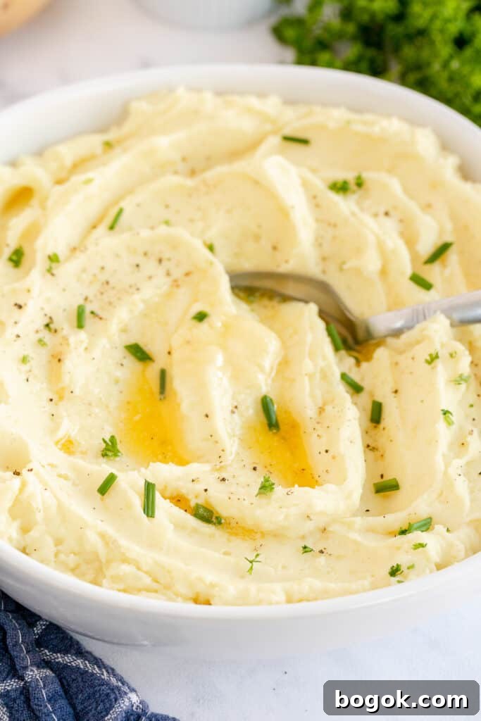 A white bowl filled with mashed potatoes topped with melted butter.