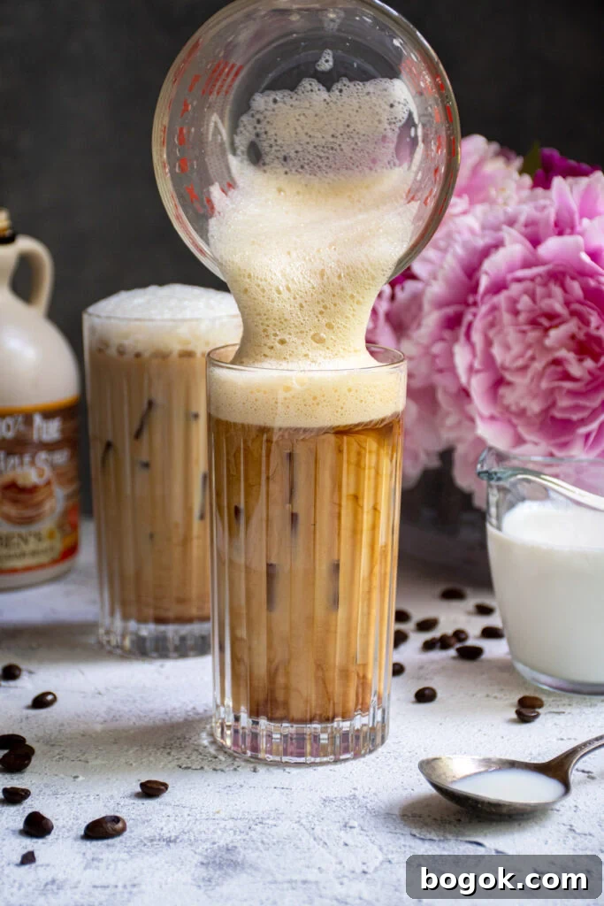 Salted Maple Foam being poured into a glass of cold brew coffee.