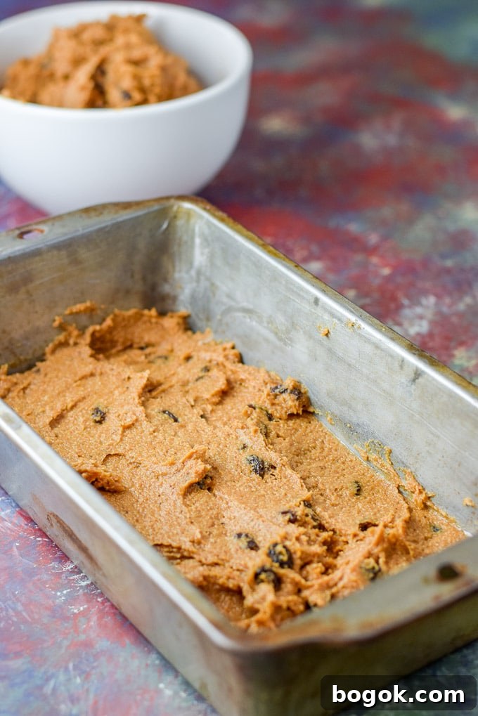 Pumpkin batter spread in a greased pan ready for the layering. There is batter in the background in a white bowl