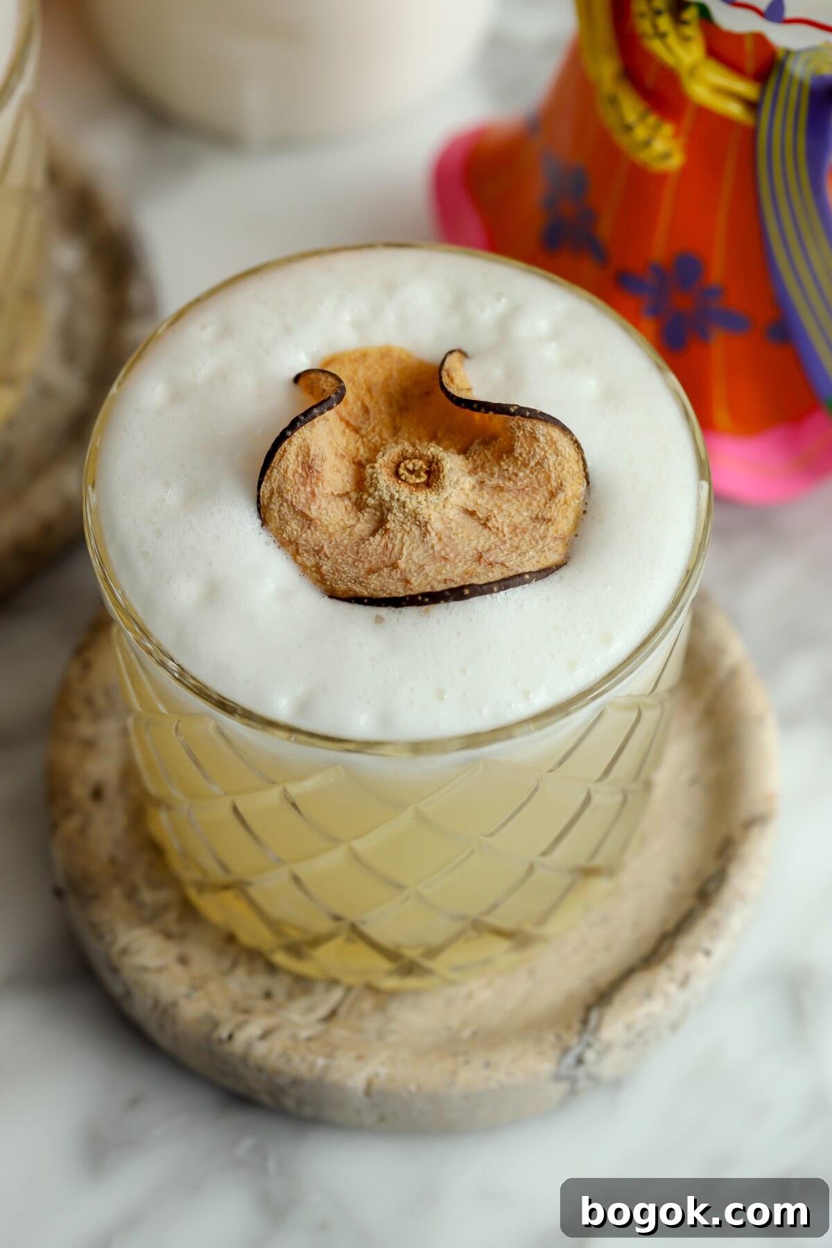 Classic Tequila Sour Cocktail Recipe — How to Make It Perfectly 3 A beautiful cocktail with a foam top, garnished with a dried pear.