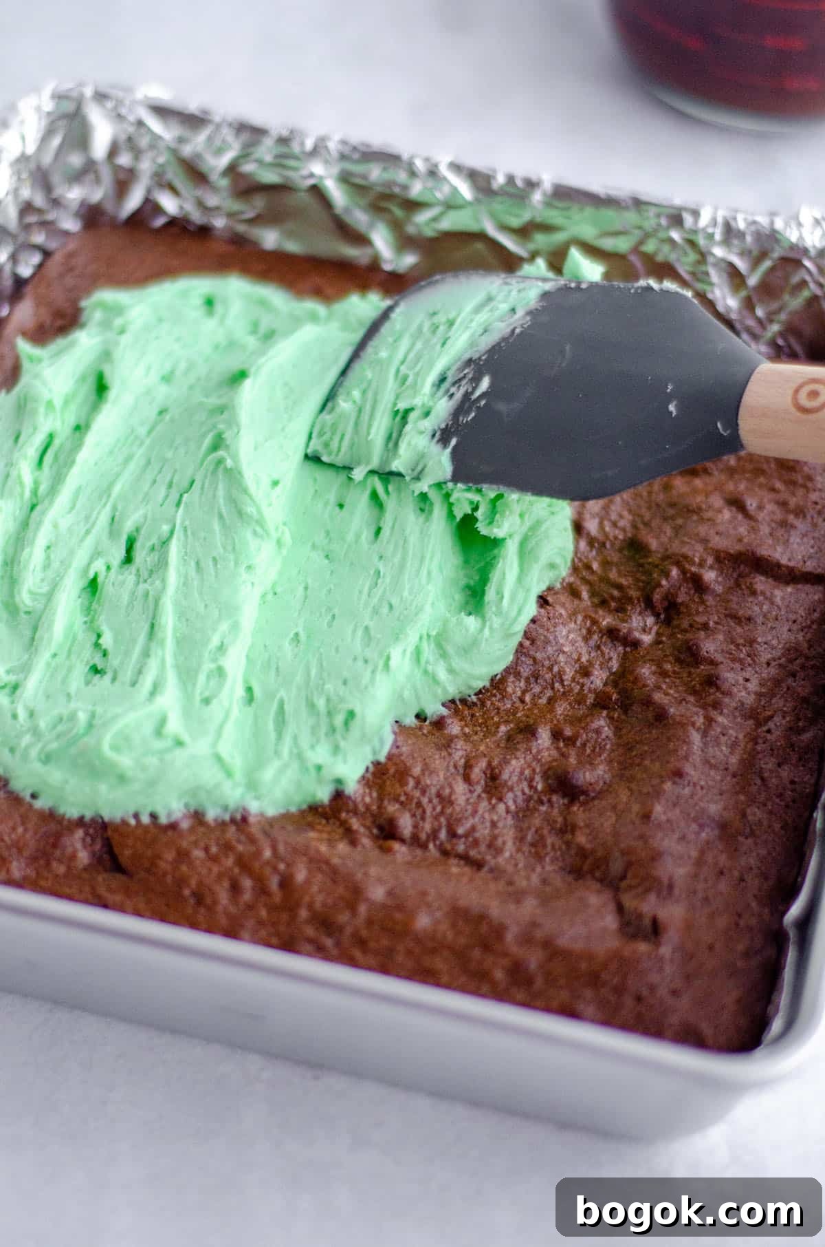 Decadent Mint Chocolate Brownie Recipe for Rich, Fudgy Treats 5 spatula spreading green mint buttercream onto brownies