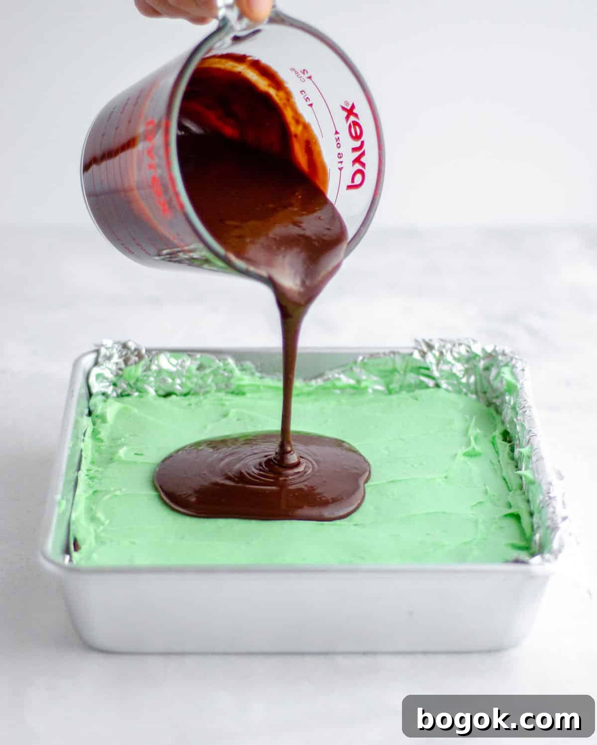 Decadent Mint Chocolate Brownie Recipe for Rich, Fudgy Treats 6 pouring chocolate onto mint layer of mint chocolate brownies