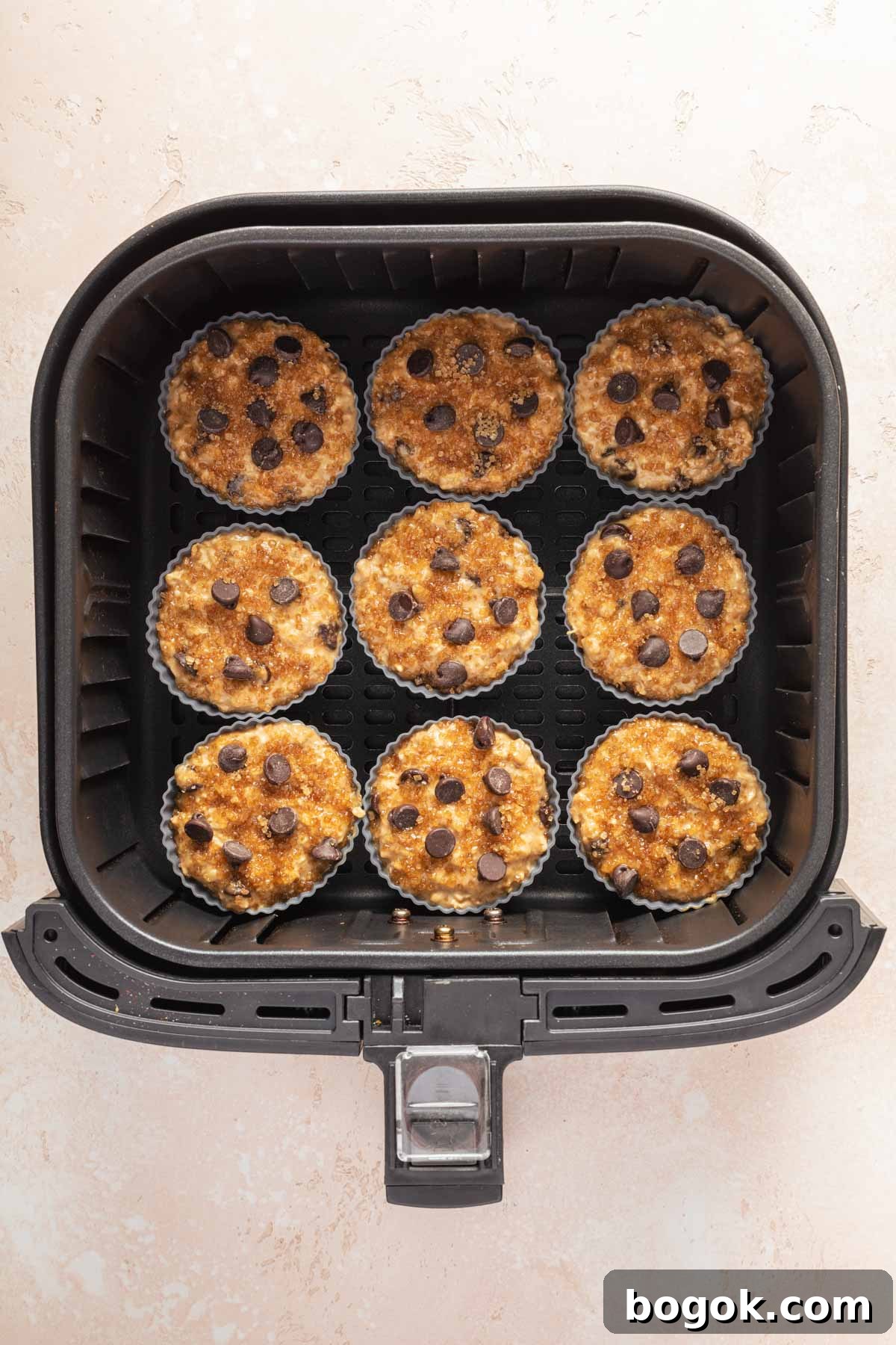 Silicone muffin cups filled with batter and arranged in the air fryer basket.