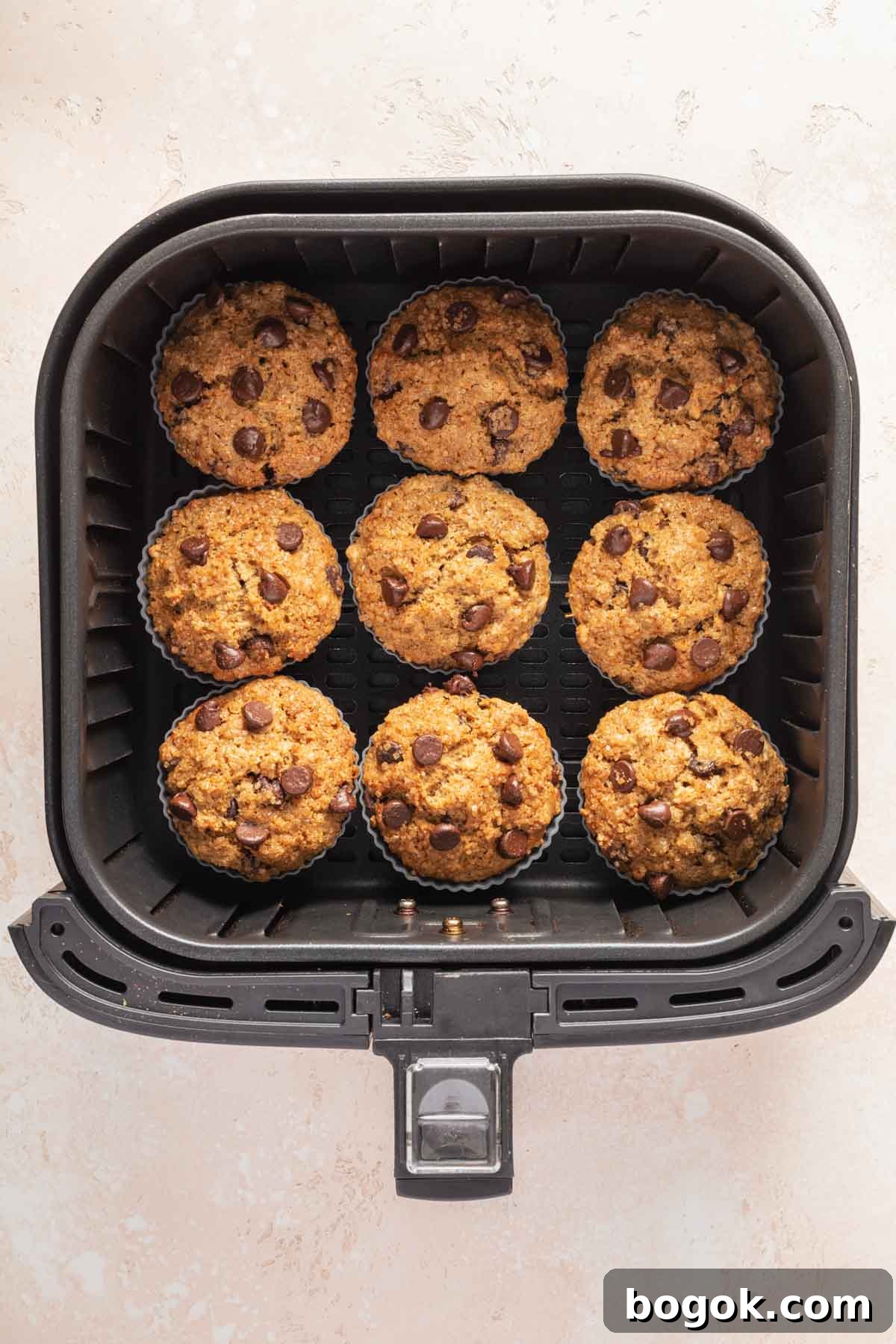 Baked chocolate chip muffins in an air fryer basket.