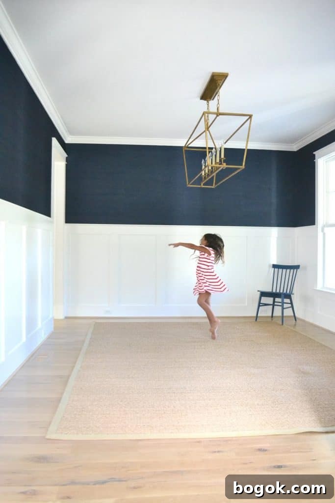 girl dancing in a dining room with navy grasscloth wallpaper