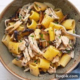 Simple chicken and pasta dish with Marsala wine sauce in brown bowl on table.