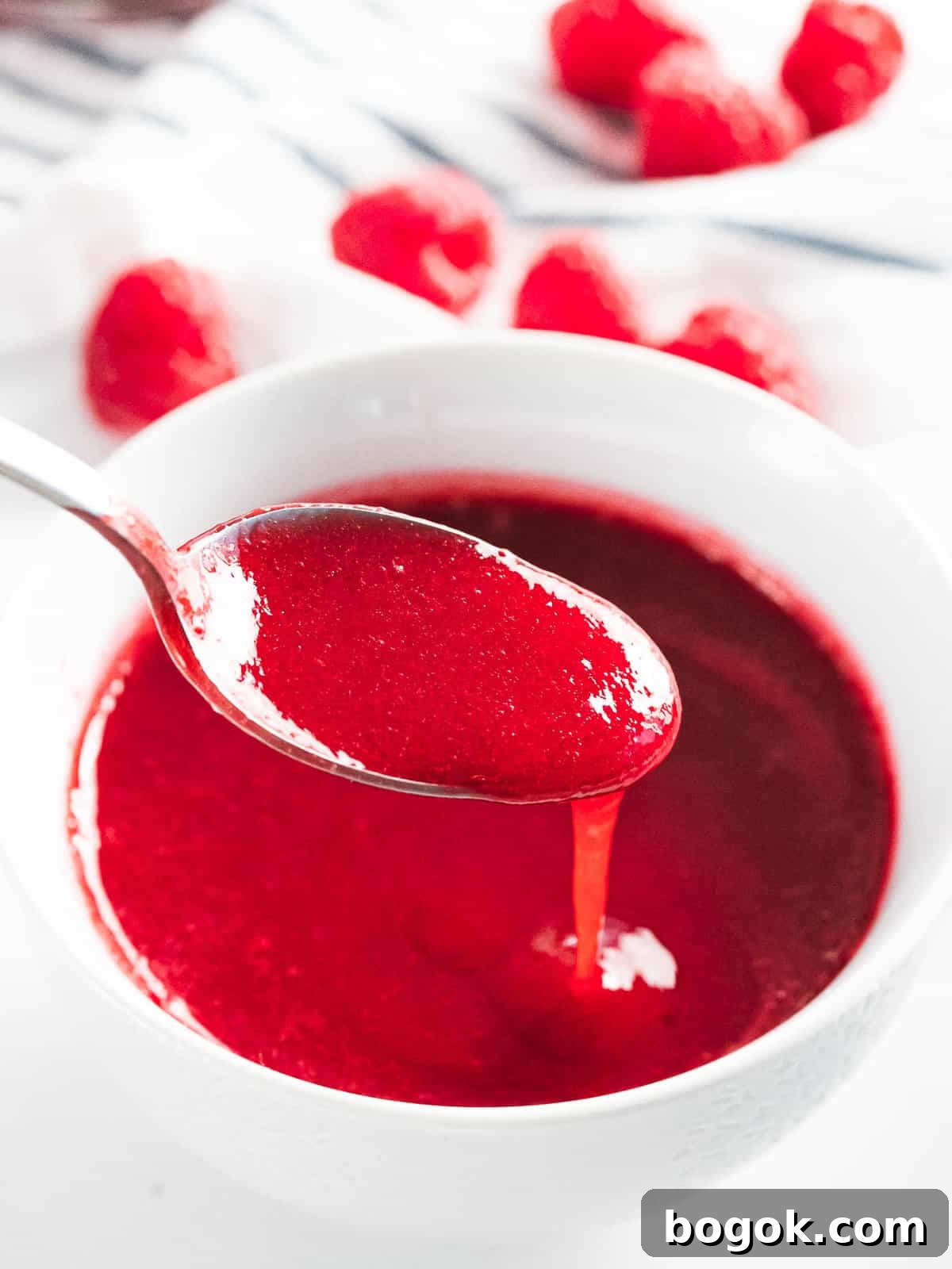 Raspberry sauce drizzled off a spoon.