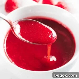 Raspberry sauce poured off a spoon.