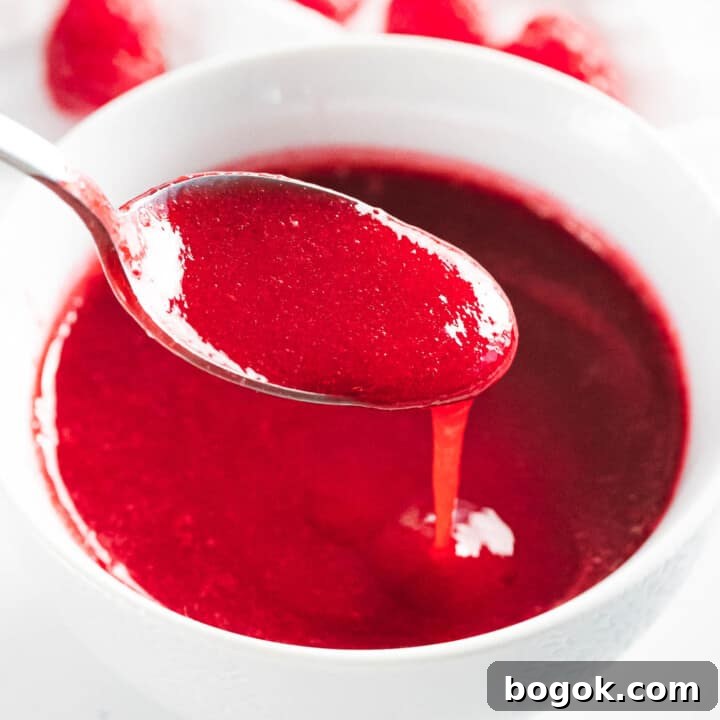 Raspberry sauce poured off a spoon.