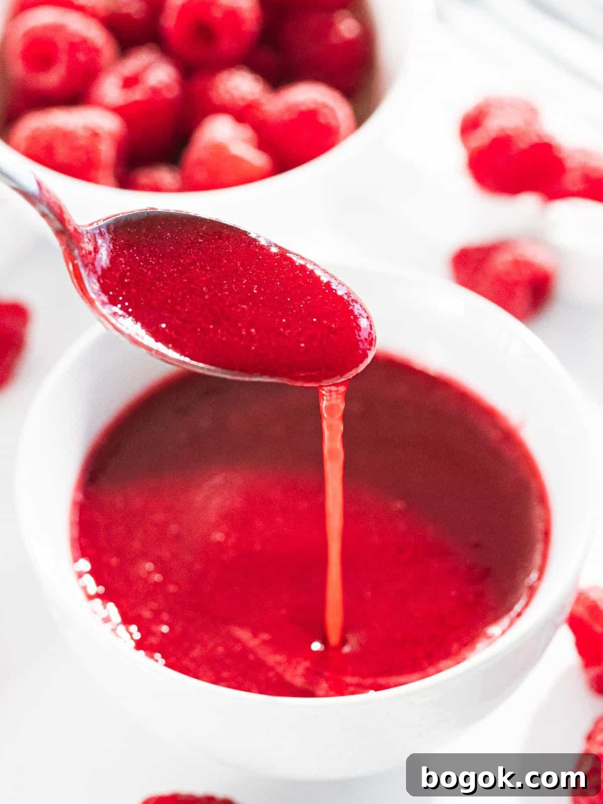 Raspberry sauce poured off a spoon to show smooth texture.