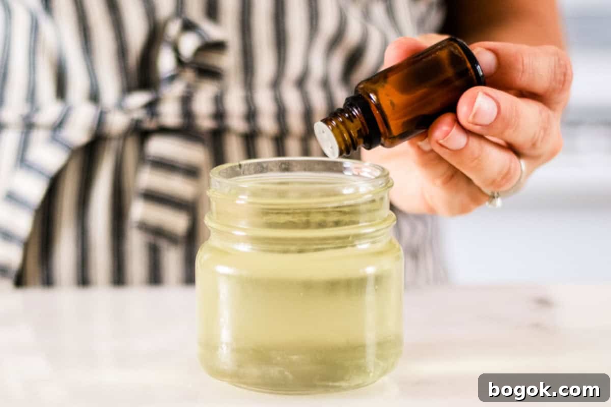 Adding essential oils to a jar of melted wax.