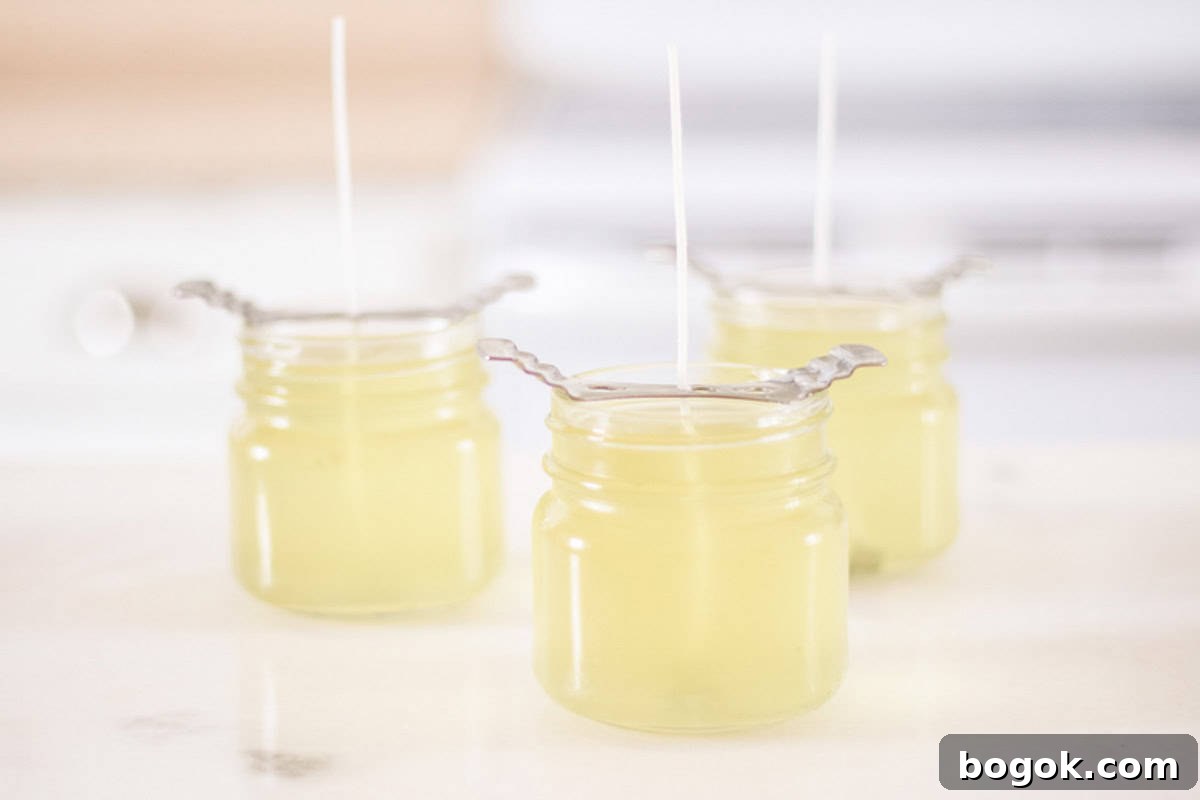 Candles with wick holders cooling on a countertop.