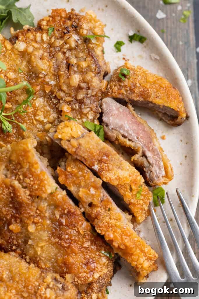 Overhead view of crispy beef schnitzel, sliced thin, with one piece on its side to show the meat.