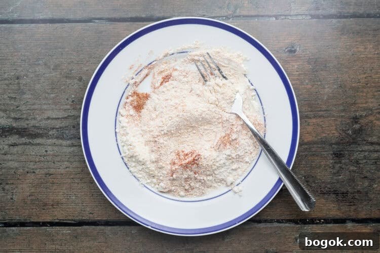 Overhead view of breading mixture for beef schnitzel on a plate with a fork.