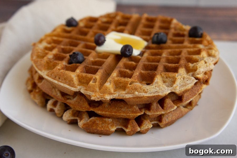 a stack of whole wheat waffles with butter and blueberries
