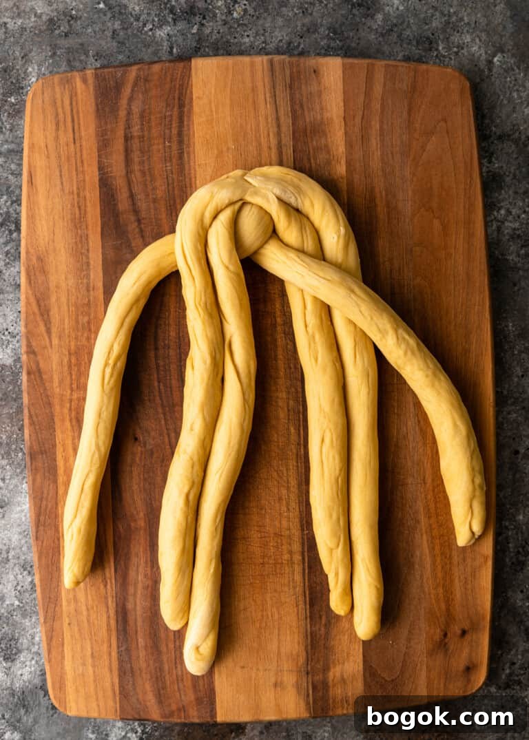 Authentic Challah Recipe: Soft, Braided Jewish Bread Tutorial 14 overhead process shot: dough rolled into six equal ropes tapered edges in the middle dough being braided
