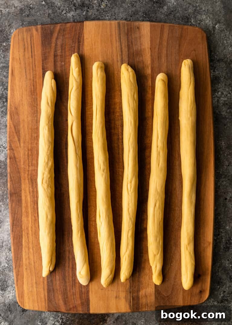 Authentic Challah Recipe: Soft, Braided Jewish Bread Tutorial 9 overhead process shot: dough rolled out to 6 18-inch ropes on cutting board