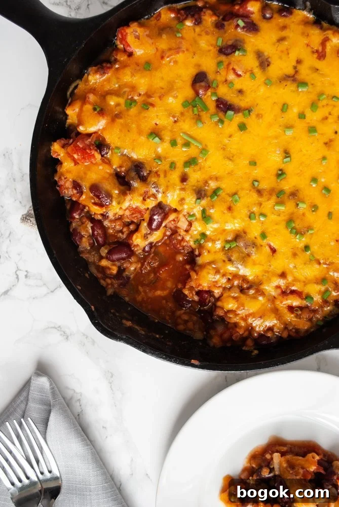 A top view of a skillet filled with lentil casserole topped with melted cheese.