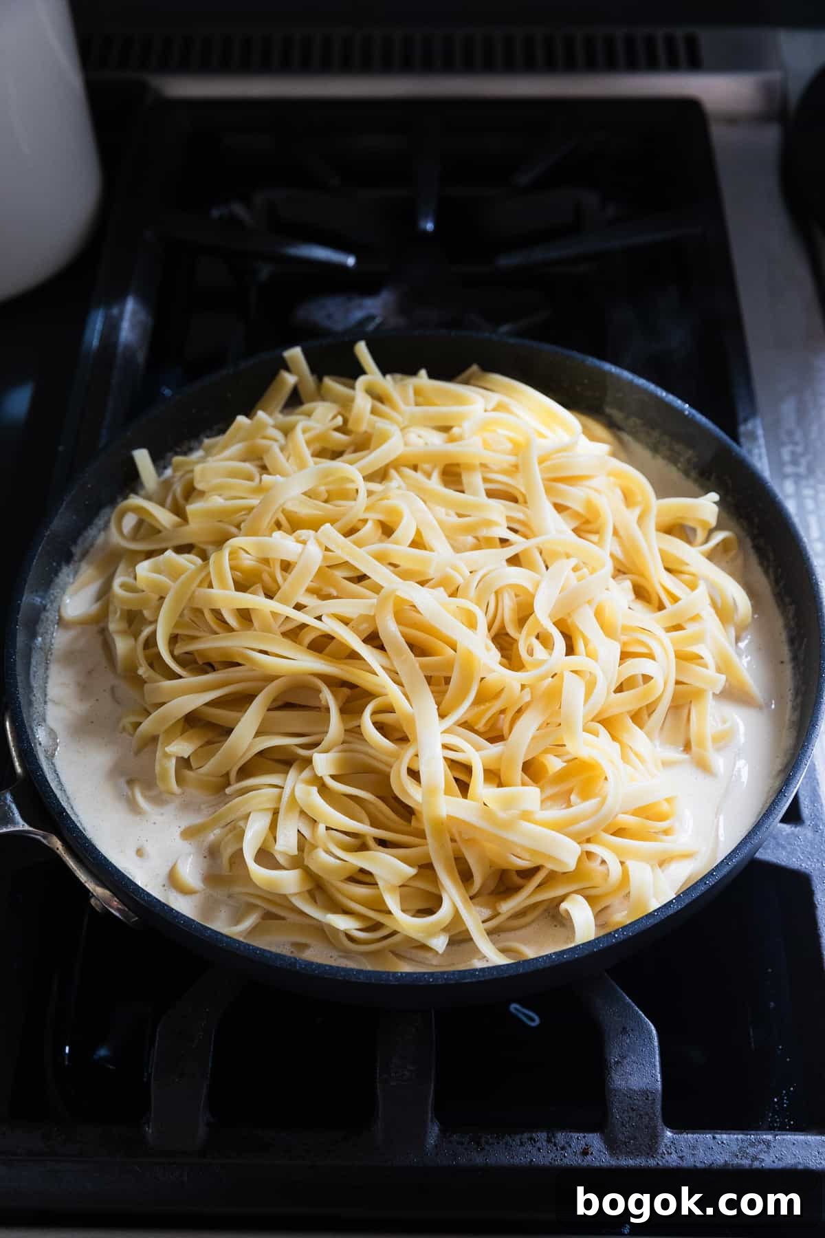 Lighter Chicken Fettuccine Alfredo Recipe (Olive Garden Style) 9 Adding cooked fettuccine noodles to alfredo sauce.