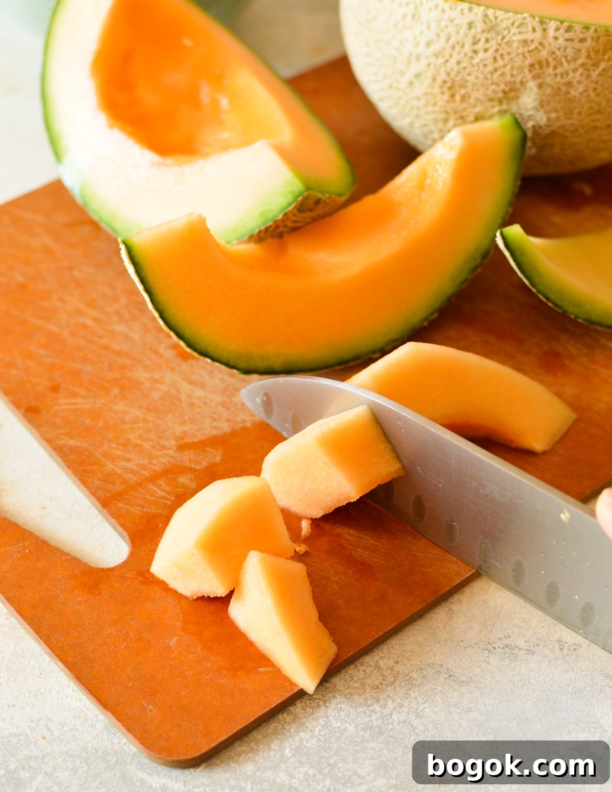 Refreshing Cantaloupe Juice Recipe: Cold, Natural & Delicious 9 knife cutting cantaloupe into chunks.