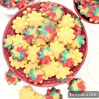 Spritz cookies, some plain and some colored, on a red plate.