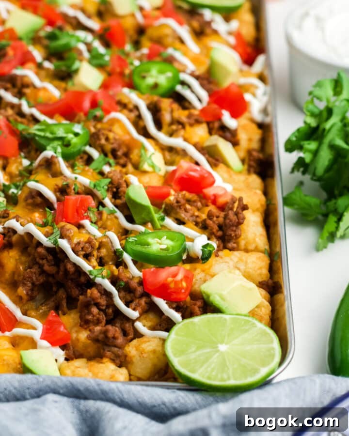 Totchos on a baking sheet garnished with lime slices.