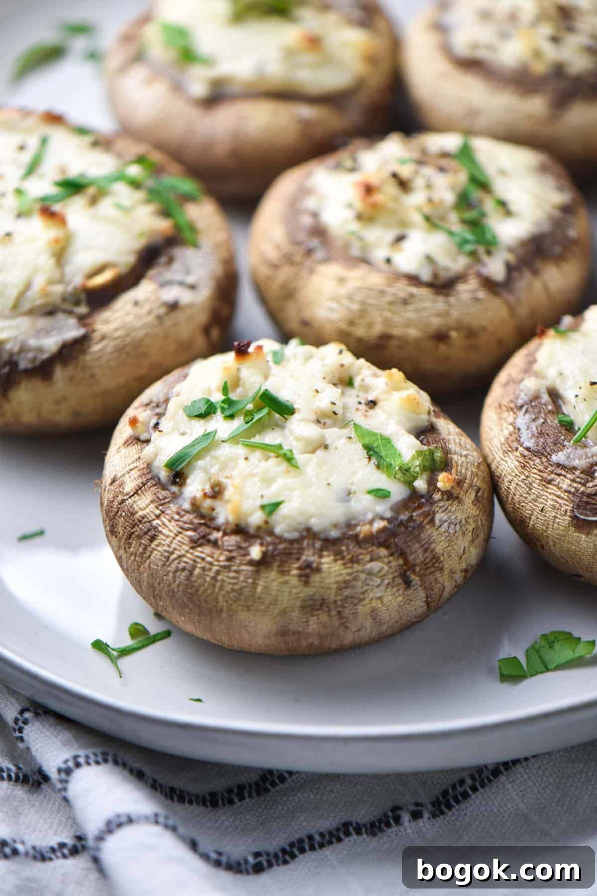 Boursin-Stuffed Mushrooms with Garlic and Herbs 8 A Boursin stuffed mushroom on a plate with cheese melting off the sides.