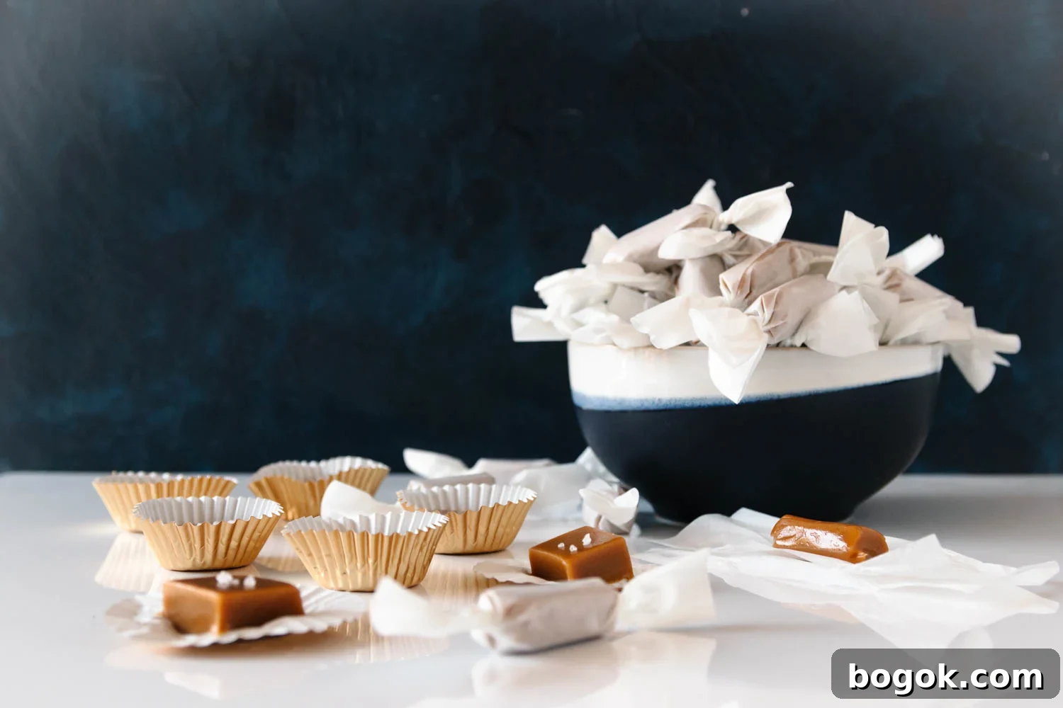 Creamy Goat Milk Caramels: Rich Handmade Candy Recipe 3 horizontal image of the caramels wrapped and on a glossy white surface for staging