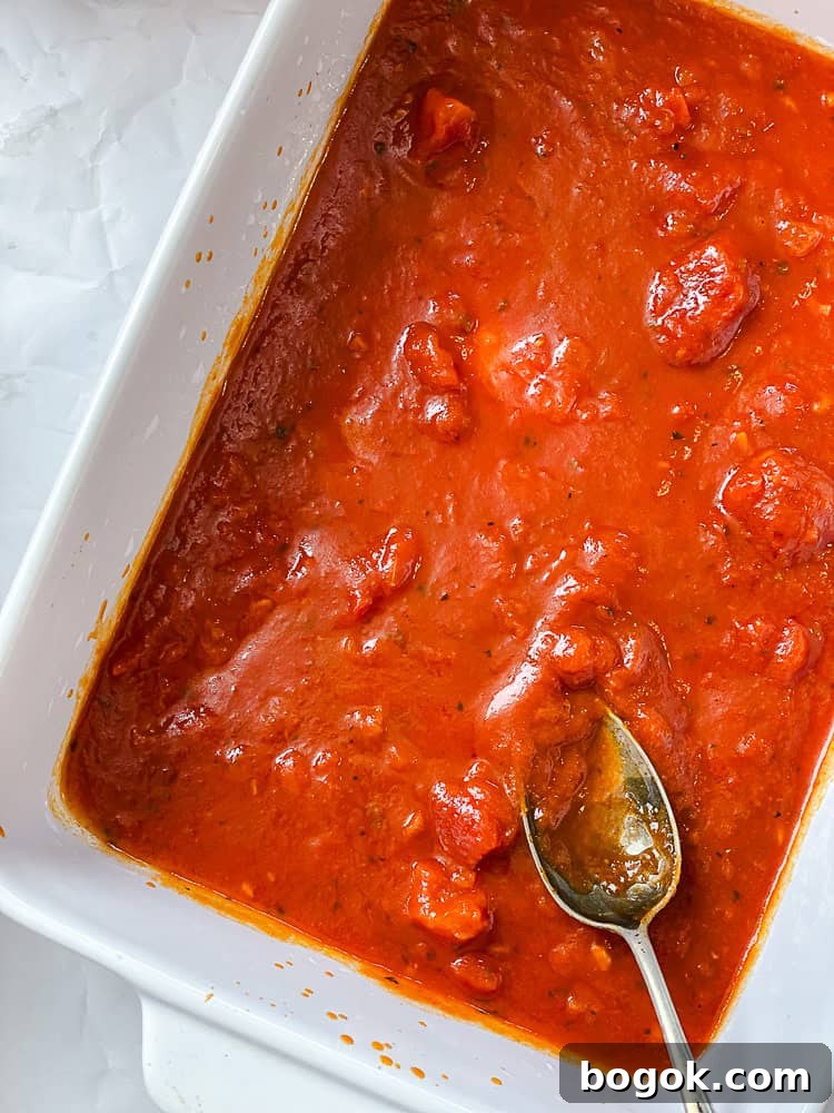 marinara sauce spread on the bottom of a baking dish.