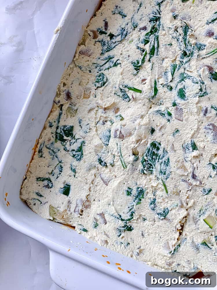 tofu ricotta spread over lasagna noodles in a baking dish.