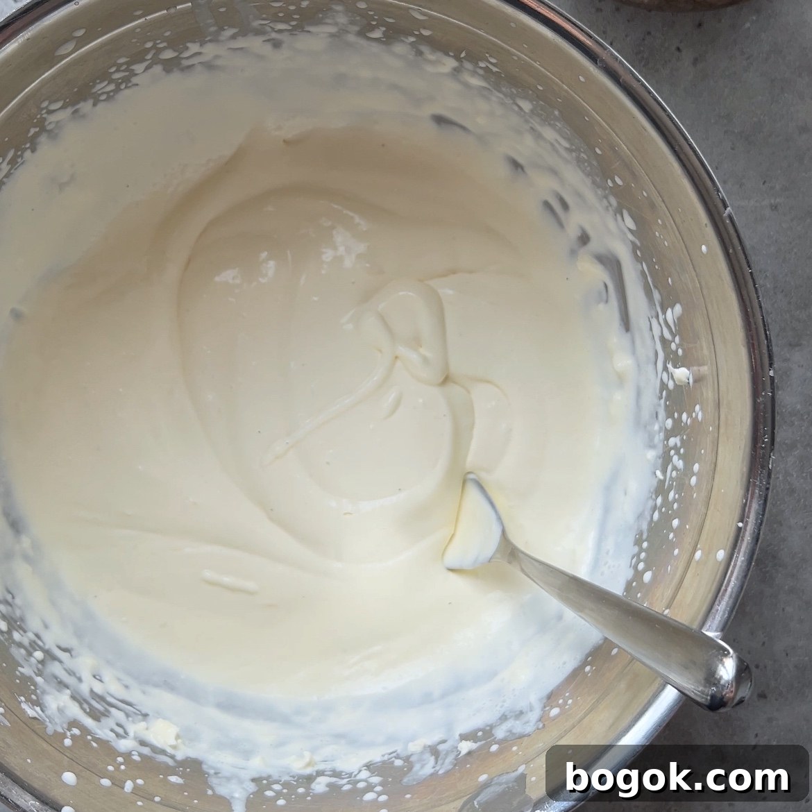 A stainless steel bowl filled with mascarpone and whipped cream mixed till soft peaks formed.