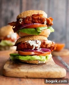 two chicken sandwich stacked on each other on wooden chopping board with blue cheese sauce dripping out