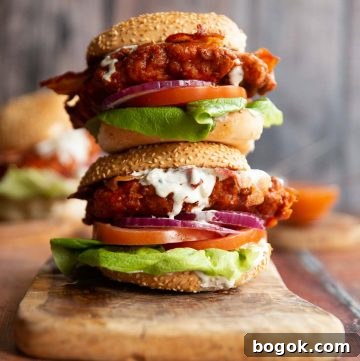 two chicken sandwich stacked on each other on wooden chopping board with blue cheese sauce dripping out