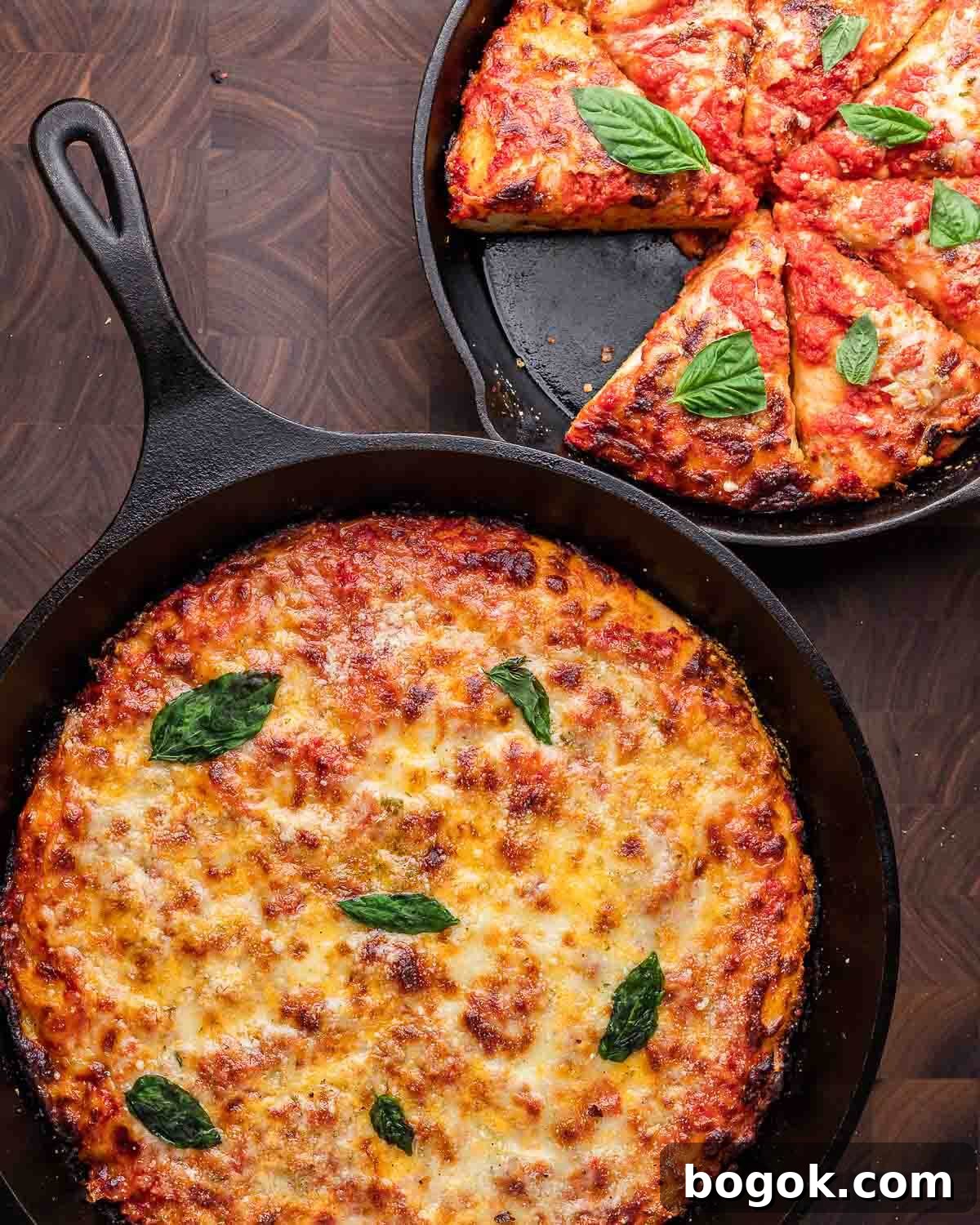 Crispy Cast-Iron Skillet Pizza Recipe 2 Overhead shot of 2 cast iron pan pizzas on walnut cutting board.