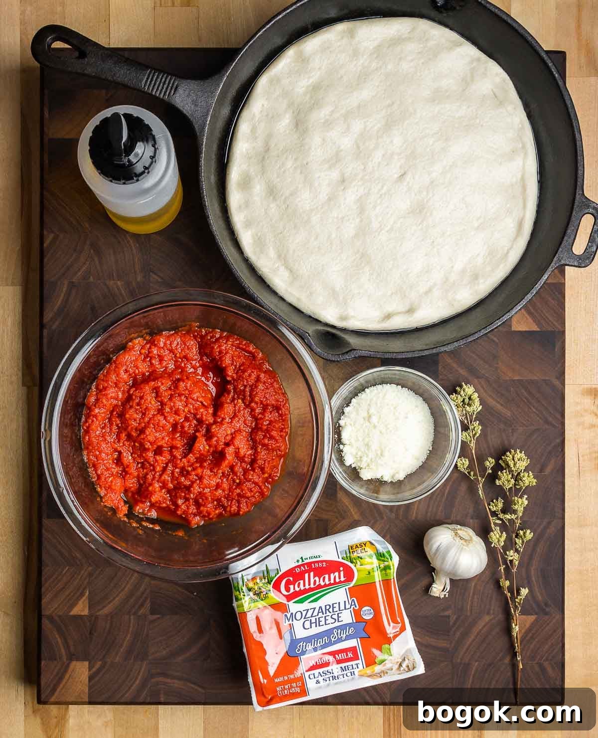 Crispy Cast-Iron Skillet Pizza Recipe 3 Ingredients shown: pizza dough in cast iron pan, olive oil. drained crushed tomatoes, Pecorino, mozzarella, garlic, and Sicilian oregano.